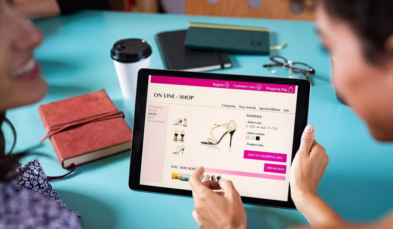 Two women holding tablet showing ecommerce store