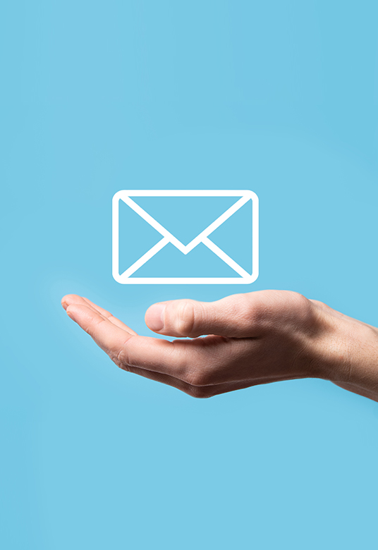 Hand holding white email graphic on top of it against blue background to show email marketing services near me