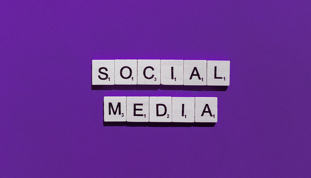 Scrabble tiles spelling out the word "social media" in a purple background.